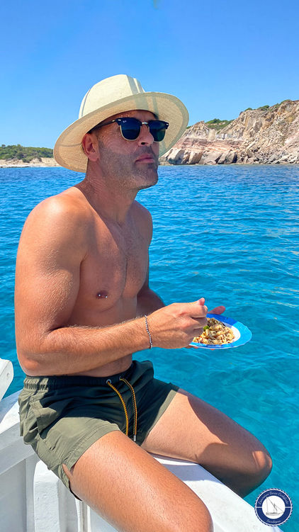 Un passeggero mangia i famosi cassulli carlofortini durante una delle escursioni in barca in Sardegna