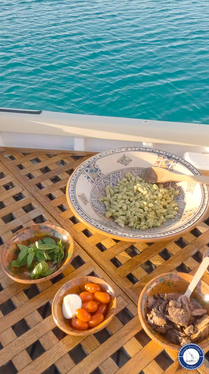 Preparazione del pranzo tipico di Carloforte in barca con pasta fresca, pomodori, basilico e tonno durante l'escursione a Carloforte