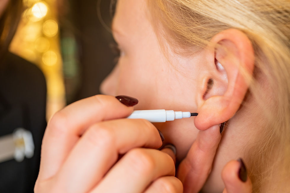 Close-up of an ear being marked for piercing with a pen by a professional medical worker i
