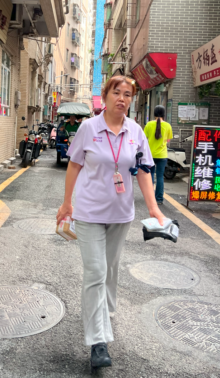 Ms. Mei (Xiao Mei), walking on the streets of a nearby urban village after afternoon work session ended, taking her packages from the village's parcel collection point