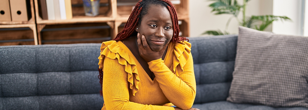 Young adult woman sitting on couch in yellow jumper