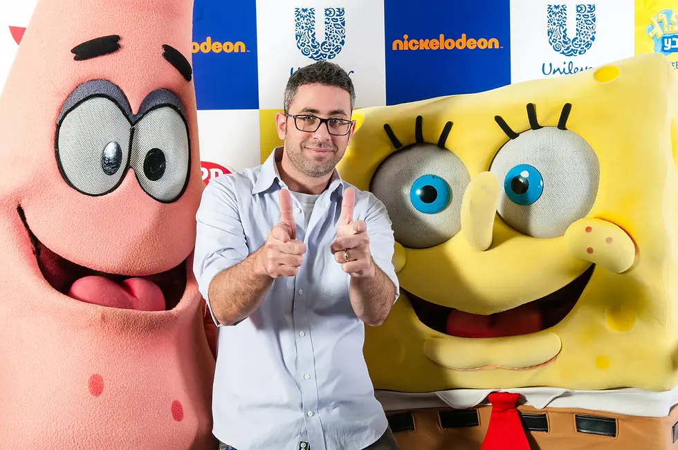 צילום אירוע שיווקי של ניקלודיאון ויוניליבר, מציג גבר מחייך בין בובות ענק של בובספוג ופטריק