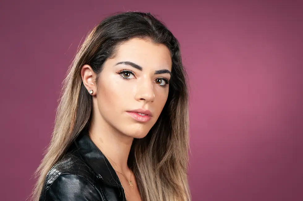 צילום פורטרט תקריב (Close-up) של צעירה בבגדי עור שחורים על רקע סגול עמוק