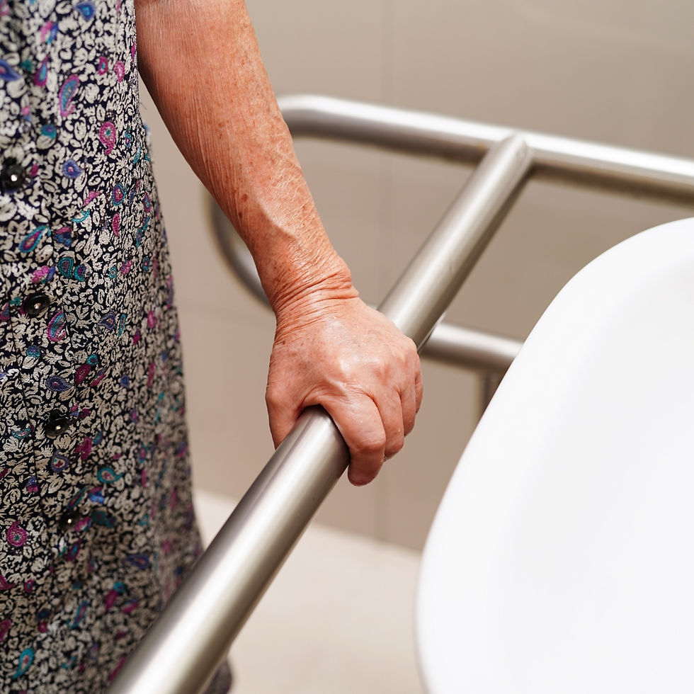 Close-up of an older adult’s hand gripping a stainless steel grab bar beside a toilet, showing steady support and the importance of bathroom safety for independent living.