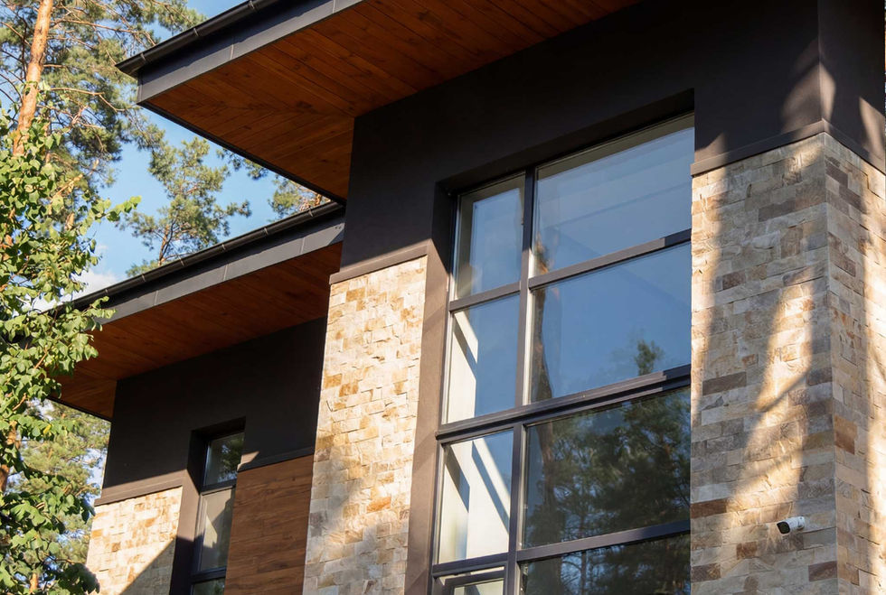 Detail view of the facade materials, including textured stone, dark wall panels, wood soffits, and modern black-framed windows.