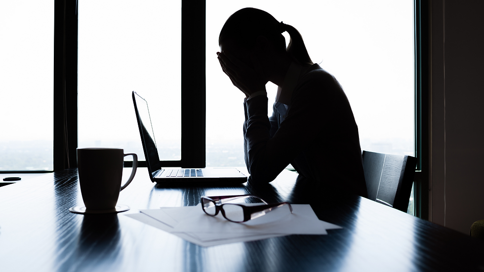 A woman slumped at a desk in a toxic work environment.
