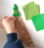 child applying green tissue paper to a triangle shaped piece of cardboard