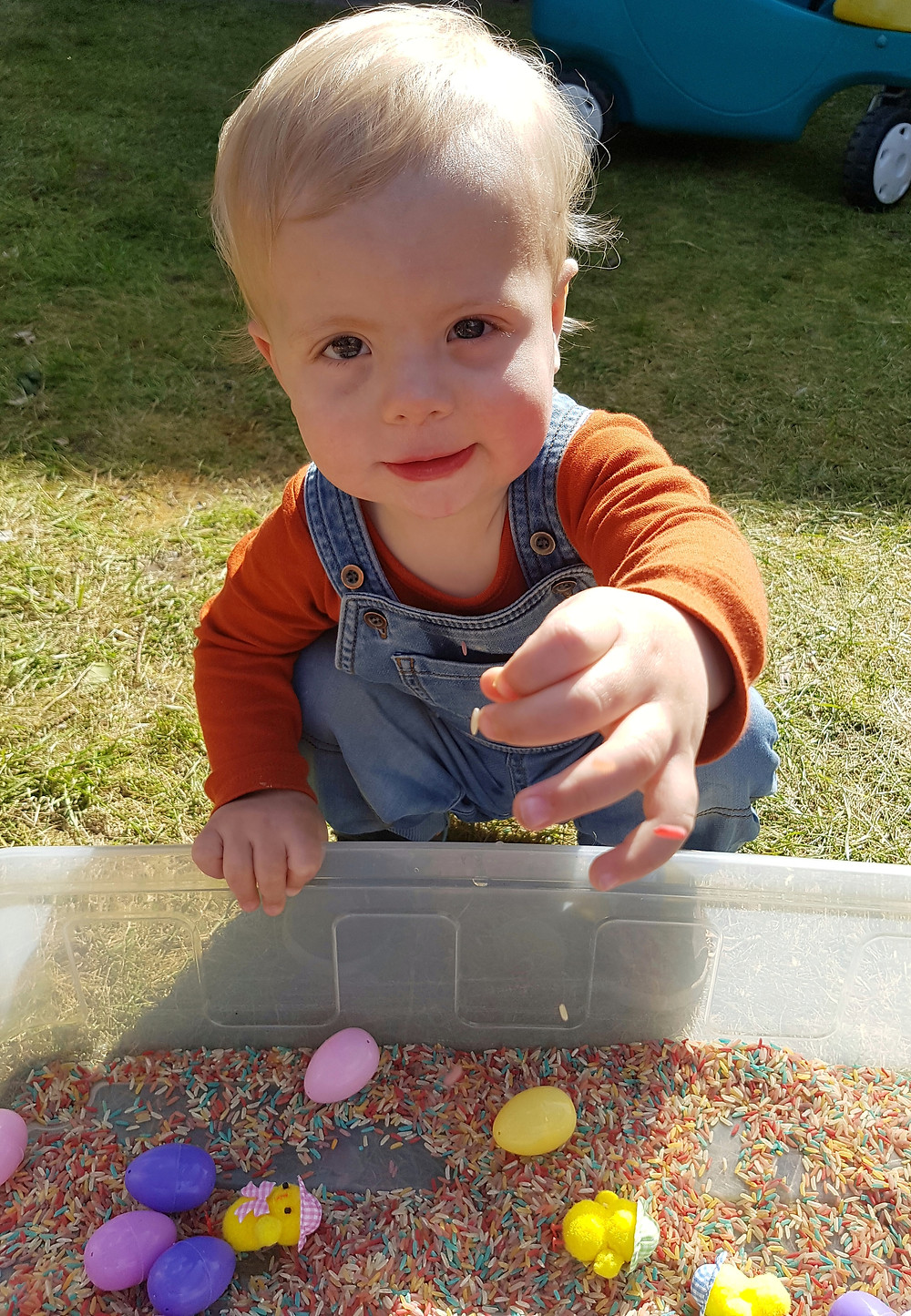 Child playing with easter rice sensory bin