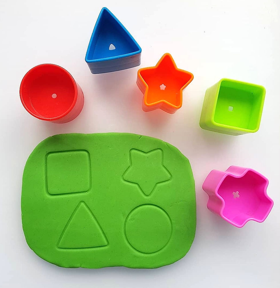 Colorful plastic shape cutters (red, blue, orange, green, pink) and green playdough.