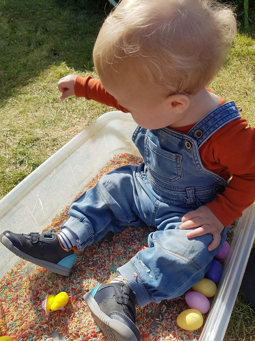 Child playing with easter rice sensory bin