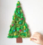 childs hand creating a small christmas tree made from colourful tissue paper