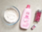 cornflower, baby lotion, pink food colouring and fake rose petals on a table