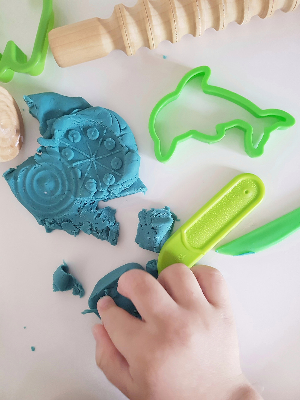 blue playdough with wooden rolling pin and green cutters