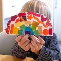 A pre-school child holding a rainbow collage