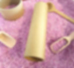 Cardboard tubes and wooden scoops on a bed of lilac rice.