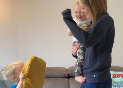 Mum and two children dance to music in lounge