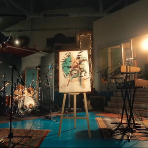 a painting on an easel in front of a drum set