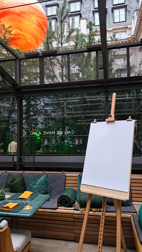 a white board is on an easel in front of a window and garden