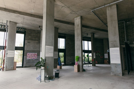 a large room with concrete pillars and various artworks placed around the room
