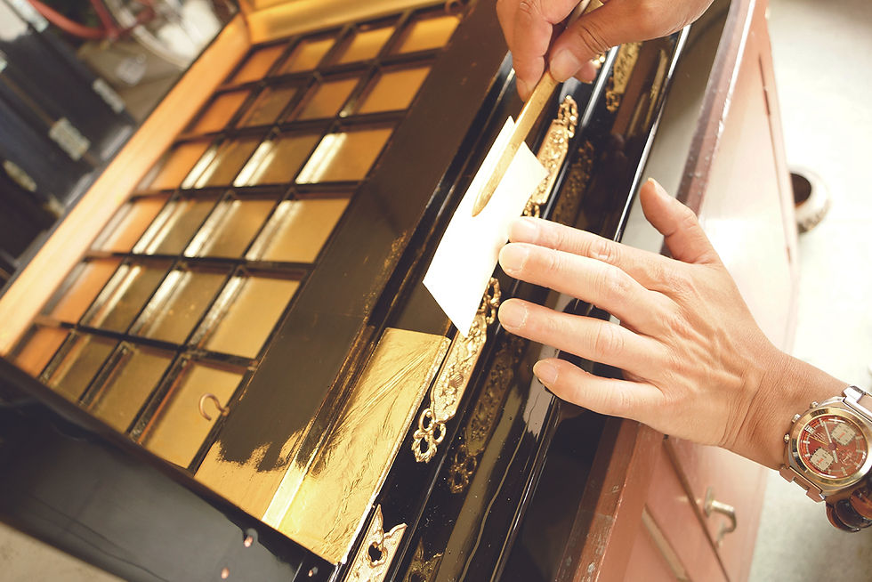 Close-up view of gold leaf being carefully applied on a Buddhist altar
