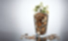 A normal drinking glass filled to the top with coins and overflowing with coins and with m
