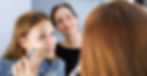 Frau trägt während eines Workshops Make Up auf und wird von einem Make Up Artist angeleitet.