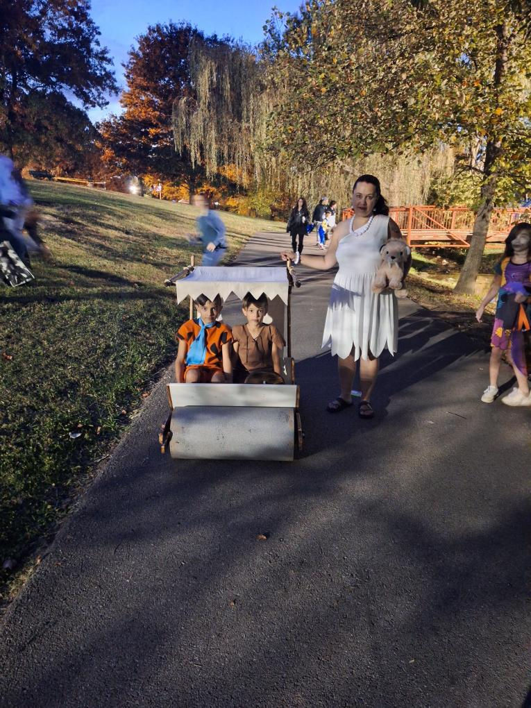 A Flintstones car with two little kids dressed as the Flintstone men with their matching mother.