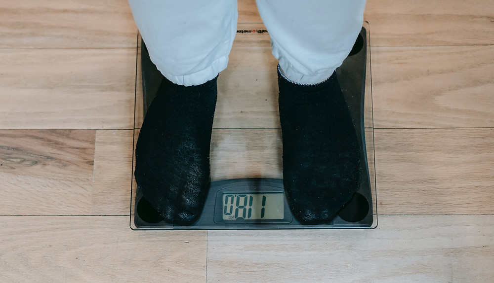 Person standing on a scale, seeing if he lost 15 pounds in a month