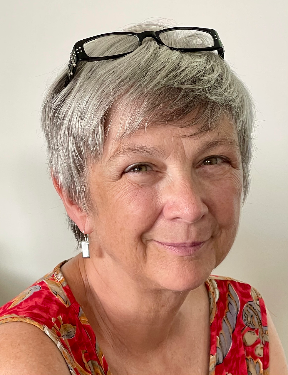 Anne with short grey hair and glasses resting on her head.