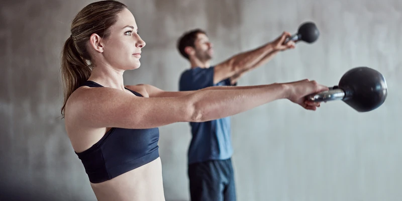 A woman and a man doing a kettlebell workout