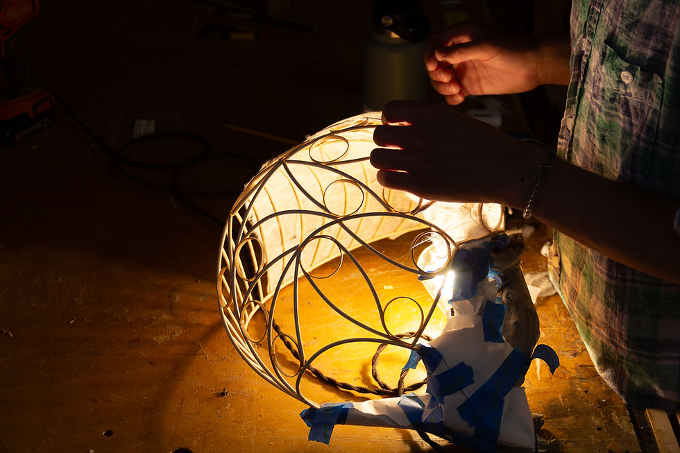 Student laying mulberry paper over a bent wood frame to make a lamp