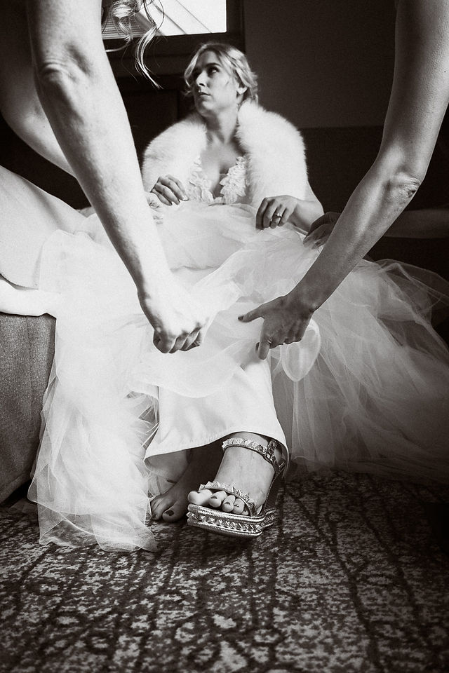 Artistic photo of bridesmaids helping bride get ready