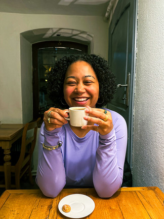 Anela in Istanbul sitting with her elbows on a small dining table, holding a small mug of Turkish coffee in her hands