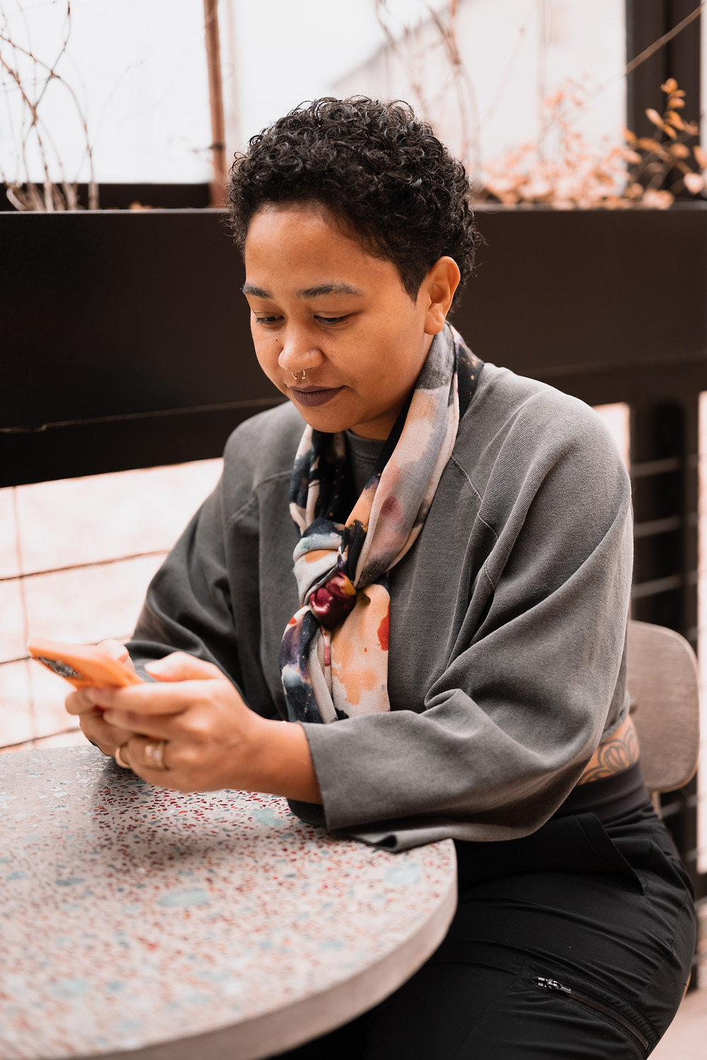 Anela sits at a cafe working on her iPhone, which she uses to create all of her content