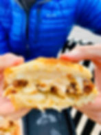 two hands holding half of a fried chicken sandwich with melted cheese dripping out