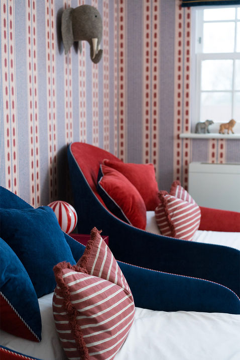 Luxury shared kids bedroom blending bold circus motifs with handcrafted upholstered beds in a London family home
