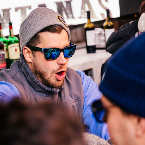 Man in beanie and sunglasses enjoying apres-ski in Aspen.