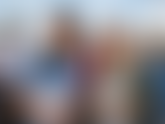 Teens holding airplane model and clipboard, smiling at airport with pilot and small plane in background. Sky is clear; atmosphere is cheerful.