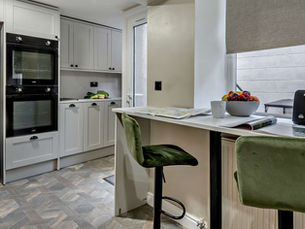 Large kitchen with 2 ovens, large fridge-freezer, breakfast bar and 2 stools.
