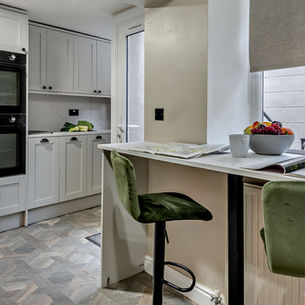 Large kitchen with 2 ovens, large fridge-freezer, breakfast bar and 2 stools.