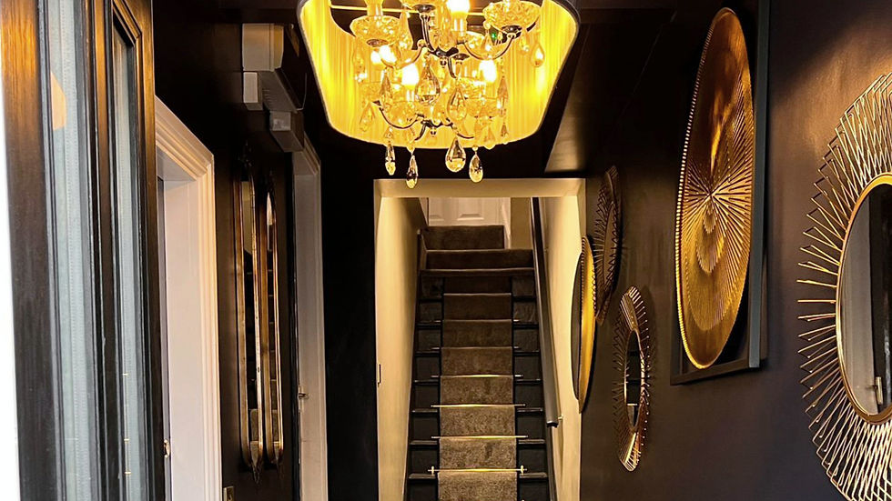 Dark blue hallway with gold accent stair rods, chandelier and gold mirrors on the walls