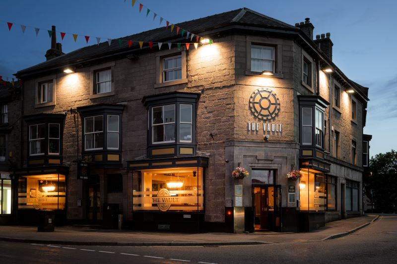 Traditional Buxton pub illuminated on a winter evening, serving hearty seasonal Derbyshire dishes.