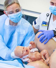 Dr. Beebe delivering a simulated newborn from a birthing simulator
