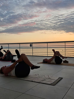 Naiset restoratiivisessa joogassa merenrannalla.