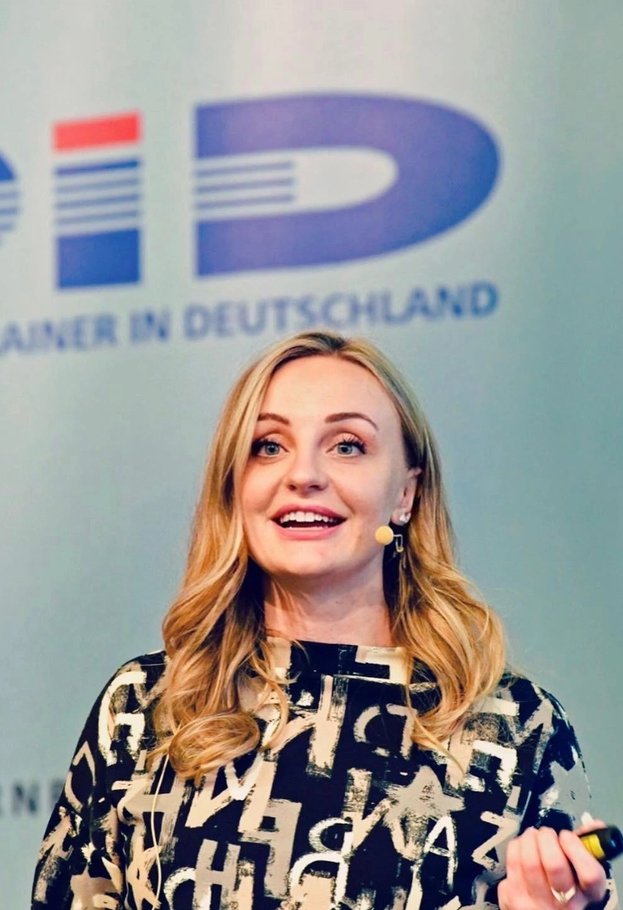 Corinna Rott speaking on stage with a presentation clicker in hand