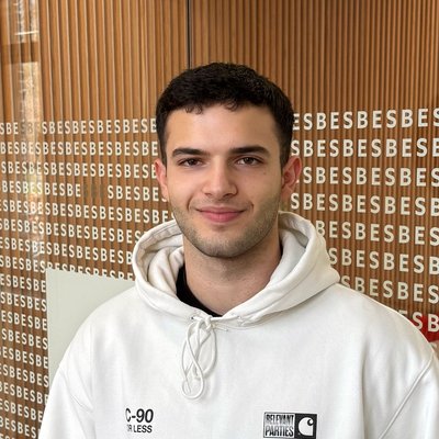 Portrait of Michael Kallas smiling, wearing a white hoodie