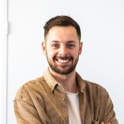 Portrait of Noah Moonen smiling, wearing a tan corduroy shirt