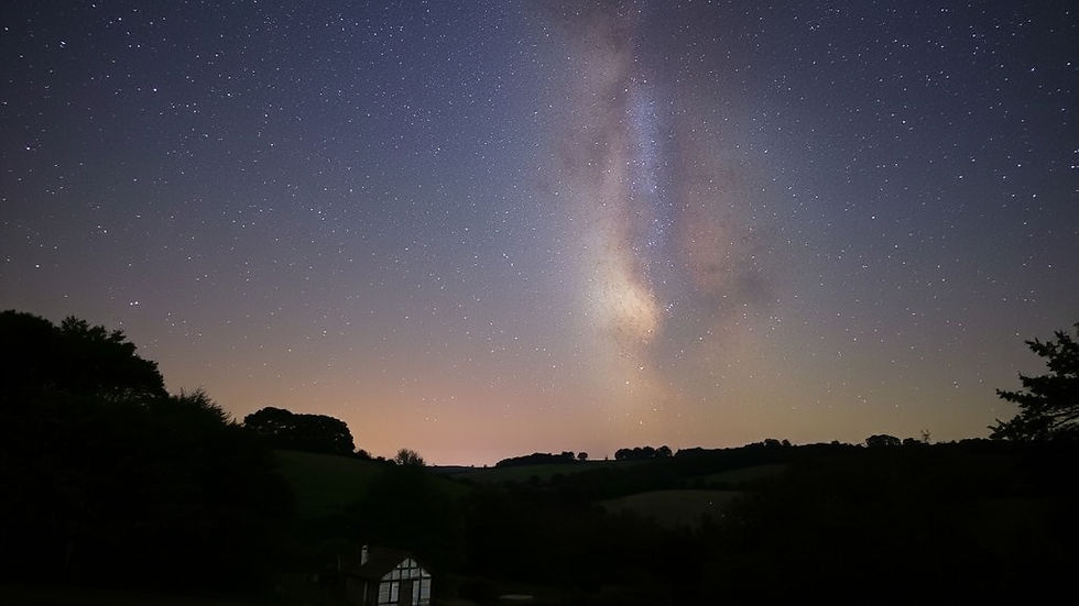 The Milky Way shines magnificently above the peaceful hills of the Cotswolds, framed by dark, star-filled skies.