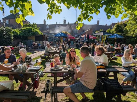 Sunny pub garden full of people socialising and drinking