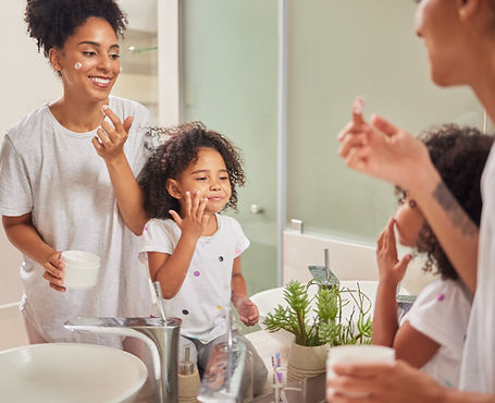 Family, skincare and love with mom and girl with facial product in bathroom mirror togethe